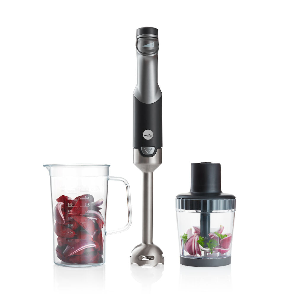 A black and silver ESSENTIAL POWER set with a powerful motor and stepless speed control, featuring three components: the blender handle, a clear measuring pitcher filled with chopped red onions, and a clear food processor attachment containing chopped vegetables, including red onions and green peppers.